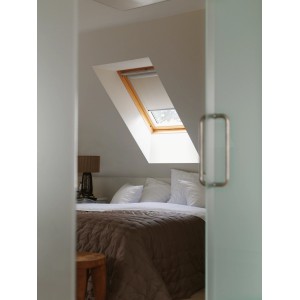 Velux Verdunkelungsrollo, beige, im Dachfenster eines Schlafzimmers.