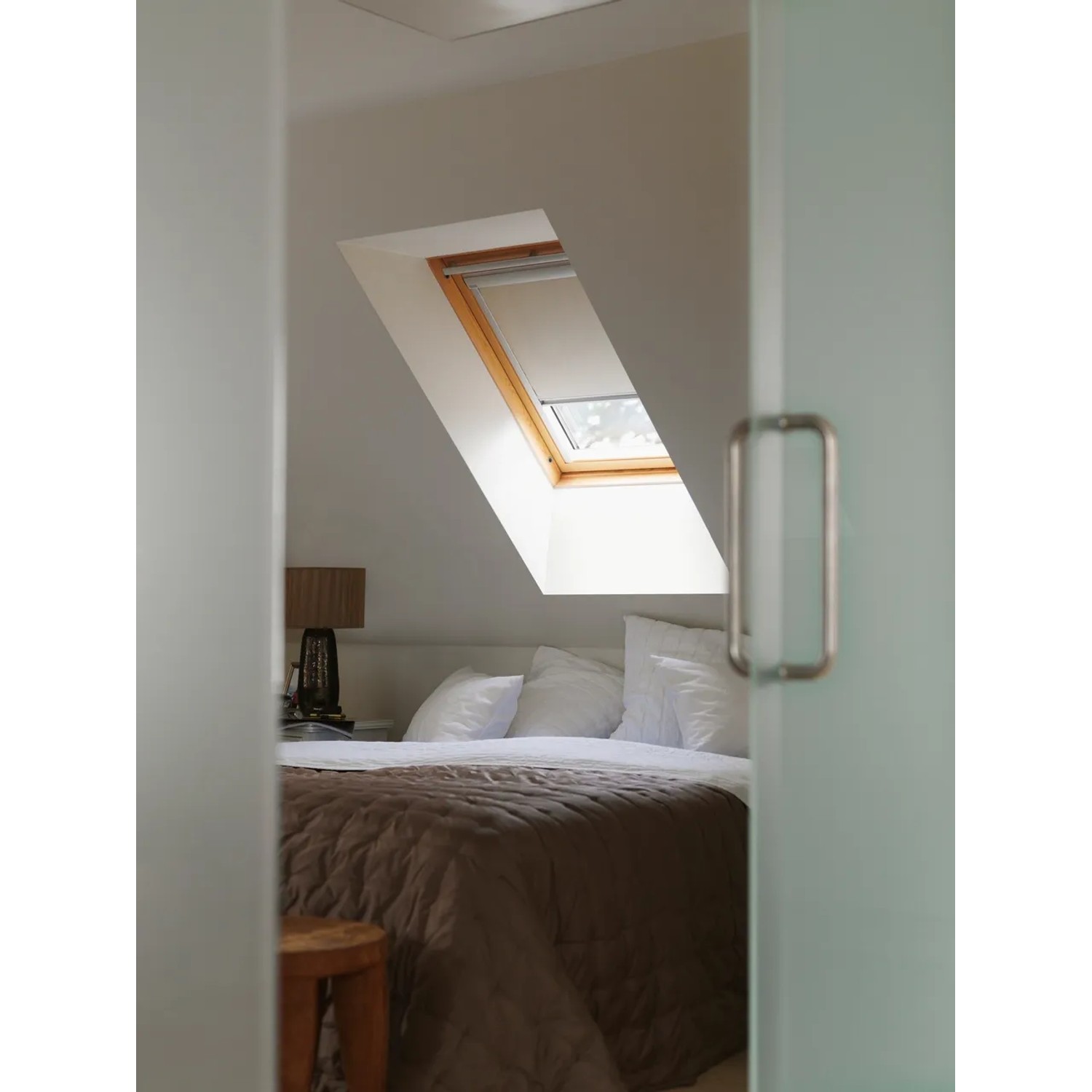 Velux Verdunkelungsrollo, beige, im Dachfenster eines Schlafzimmers.