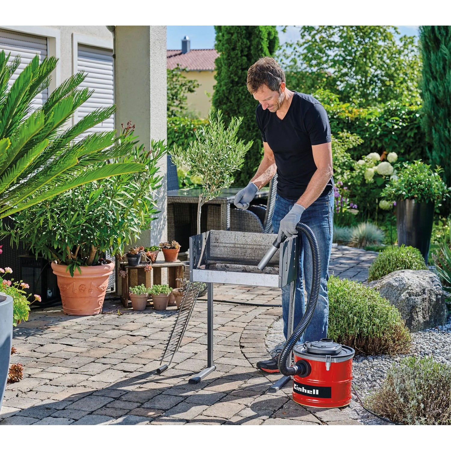 Mann reinigt Grill mit Einhell Aschesauger TC-AV 1830 D. Nass- & Trockensauger mit Metallsaugrohr.