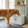 Weiße erhöhte Hundefutterstation aus MDF mit Edelstahlnäpfen und Schrankfach. Golden Retriever frisst.
