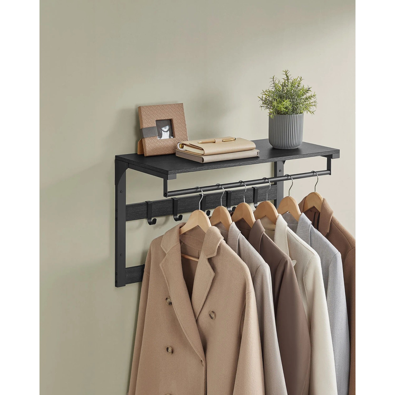Schwarze Songmics Wandgarderobe Barnet-old mit Ablage, Haken und Kleiderstange. Jacken hängen an der Garderobe.