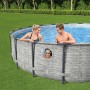 Bestway Stahlrahmenpool Set mit Familie im Garten. Runder Pool mit Fenster und grauem Steinmuster.