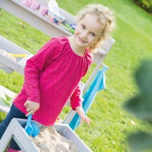 Kind spielt am roba Outdoor Spiel- & Wassertisch Tiny mit Sand und Schaufel im Garten.
