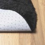 Schwarzer runder Shaggy Hochflorteppich aus Polyester mit rutschfester Unterseite auf Holzfußboden.