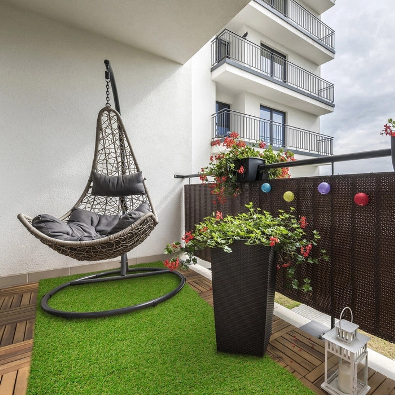 Kunstrasen Riviera 14mm auf Balkon mit Hängekorb-Sessel und Pflanzen.