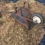 Schwarze Aquagart Unkrautfolie unter Holzhackschnitzeln mit Schubkarre im Garten.
