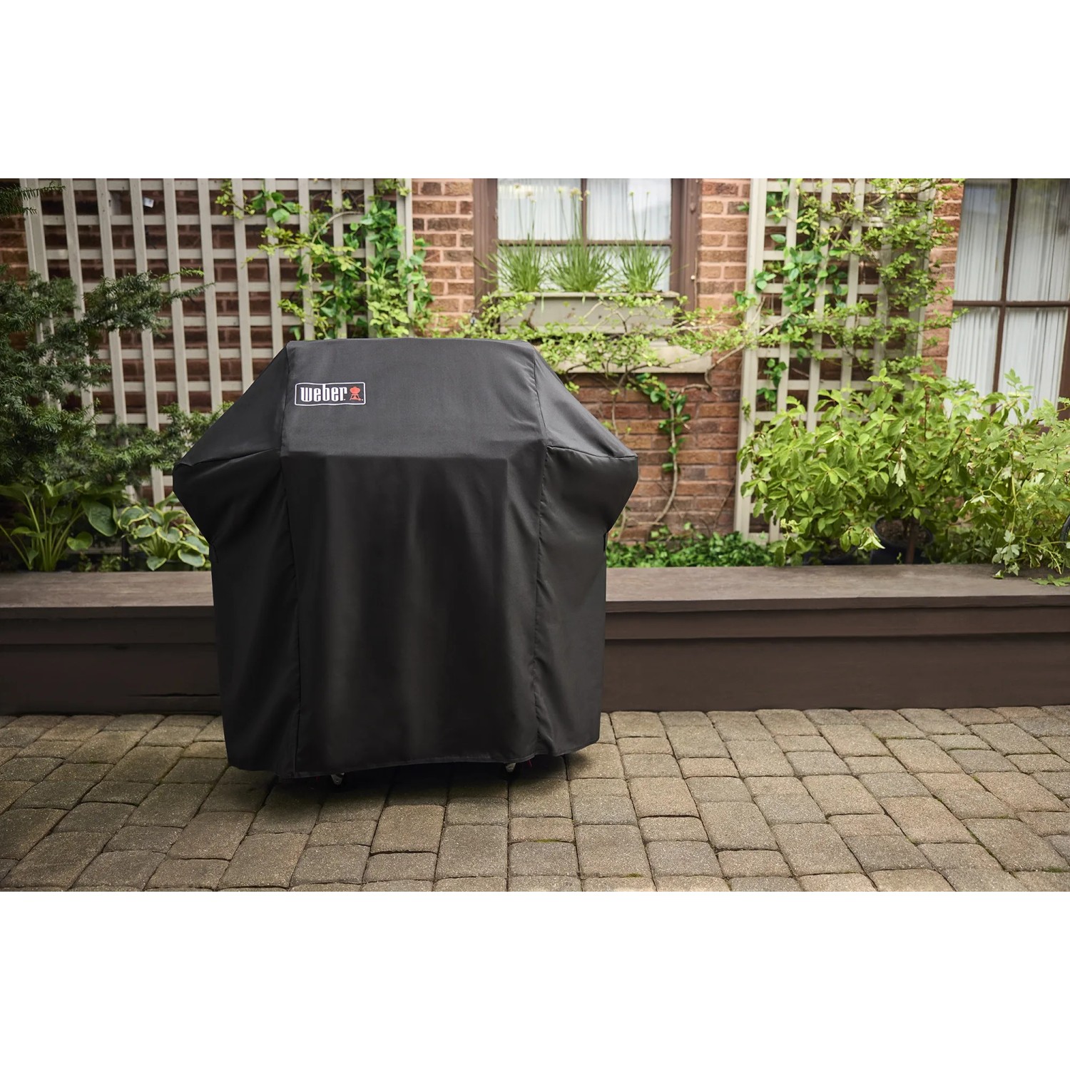Abgedeckter Weber Gasgrill E-310 Spirit 2025 Schwarz mit Schutzhülle im Garten.