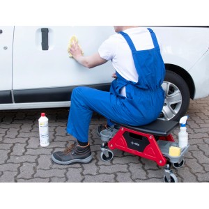 rikta Werkstatt-Rollsitz im Einsatz: Person reinigt Auto mit Werkzeug und Reiniger auf dem roten Werkstattwagen.