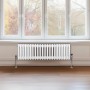Weißer 3-Säulen Heizkörper (300x1192mm) vor Fenster. Traditionelles Design für wohlige Wärme.