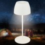Weiße Brilo LED Akku Tischleuchte Serina Mini (20 cm) vor nächtlicher Outdoor-Szene.