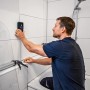 Mann nutzt Bosch Professional GMS 120-27 Ortungsgerät in Badezimmer zur Wandprüfung.