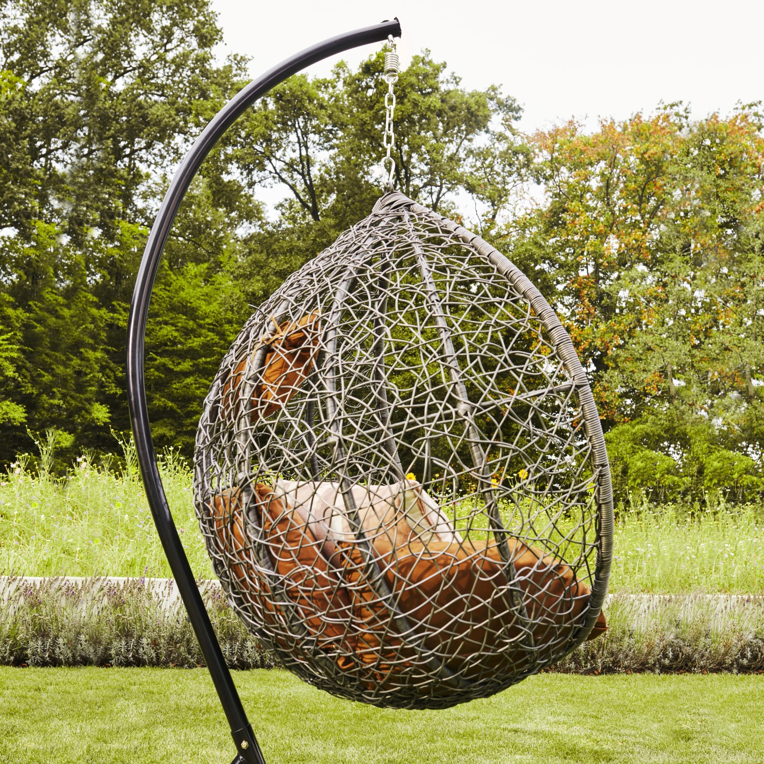Grauer Home Deluxe Hängesessel Cielo aus Polyrattan mit Regenabdeckung und Kissen.