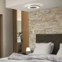 Silberne Philips Hue Being Deckenleuchte mit Dimmer im Schlafzimmer mit Steinwand und Holztüren.