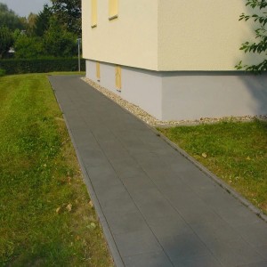 Verlegter Gehweg mit anthrazitfarbenen Gehwegplatten (30x30) mit Fase vor einem Haus.