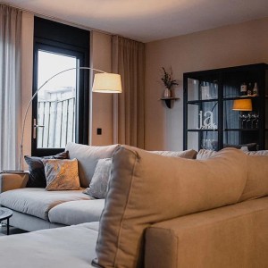 Moderne Bogenlampe Arc Basic mit grauem Stoffschirm im Wohnzimmer.