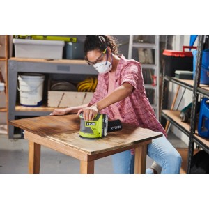 Ryobi Akku-Exzenterschleifer RROS18-0 beim Schleifen einer Holzplatte.