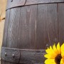 Detailaufnahme: Dunkelbraune Arves Regentonne Barrique 250 l in Holzfass-Optik mit Beschlägen und Sonnenblume.