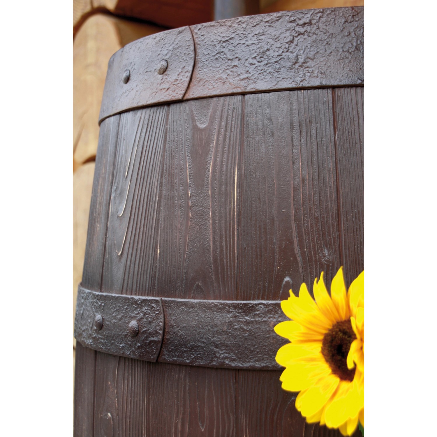 Detailaufnahme: Dunkelbraune Arves Regentonne Barrique 250 l in Holzfass-Optik mit Beschlägen und Sonnenblume.