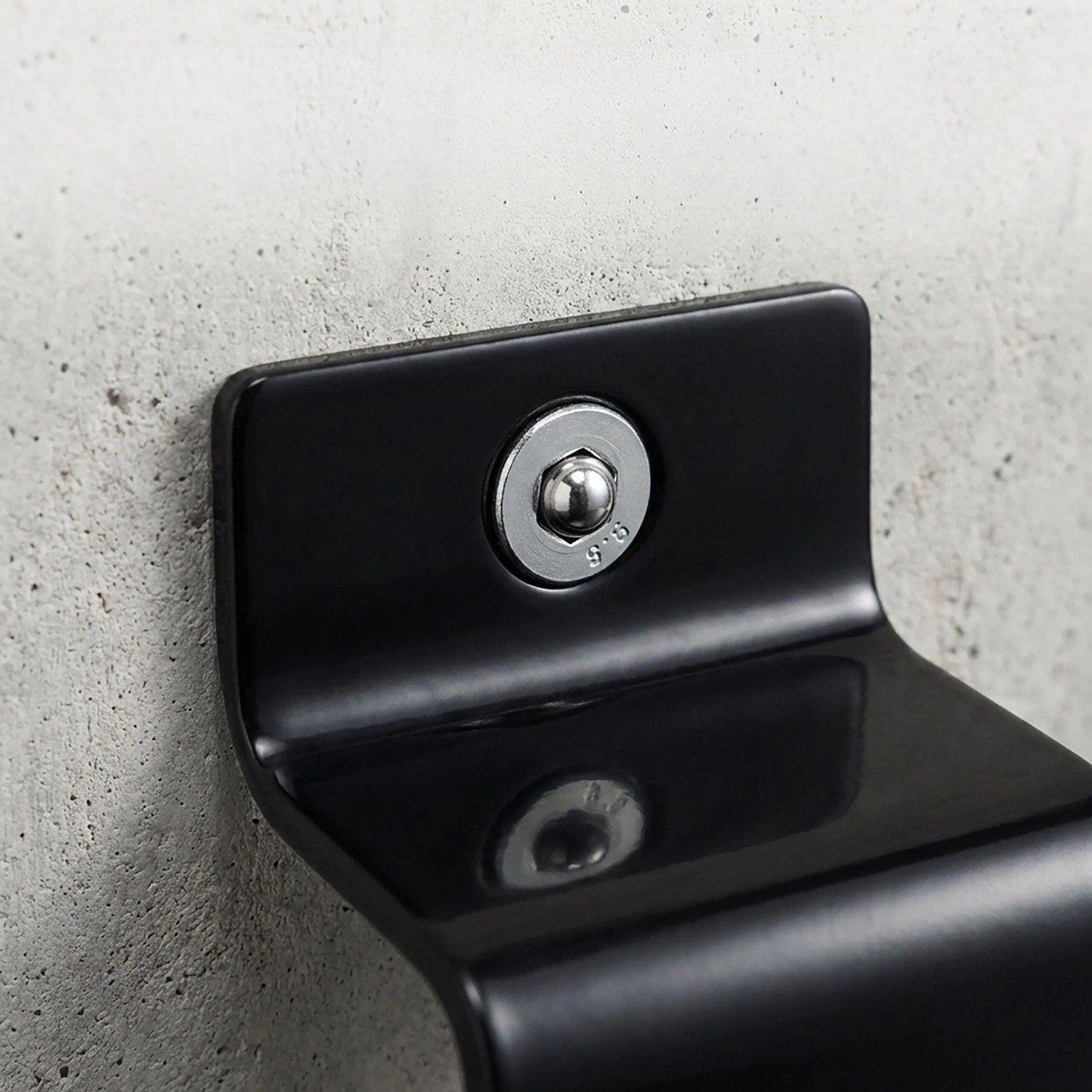 Schwarzer Relaxdays Stahl Wand- und Bodenanker mit silberner Schraube an Betonwand. Diebstahlsicherung für Fahrräder.