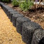 Schwarze Terrasoft Beeteinfassung aus Gummigranulat, flexibel für Gartenwege und Beete.