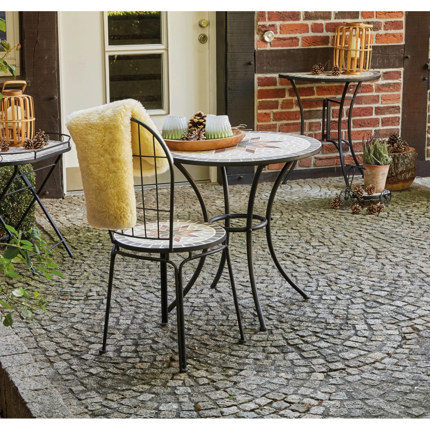 Runder, grauer Siena Garden Gartentisch Stella (Ø 70 cm) mit Stahlgestell und Mosaikmuster.