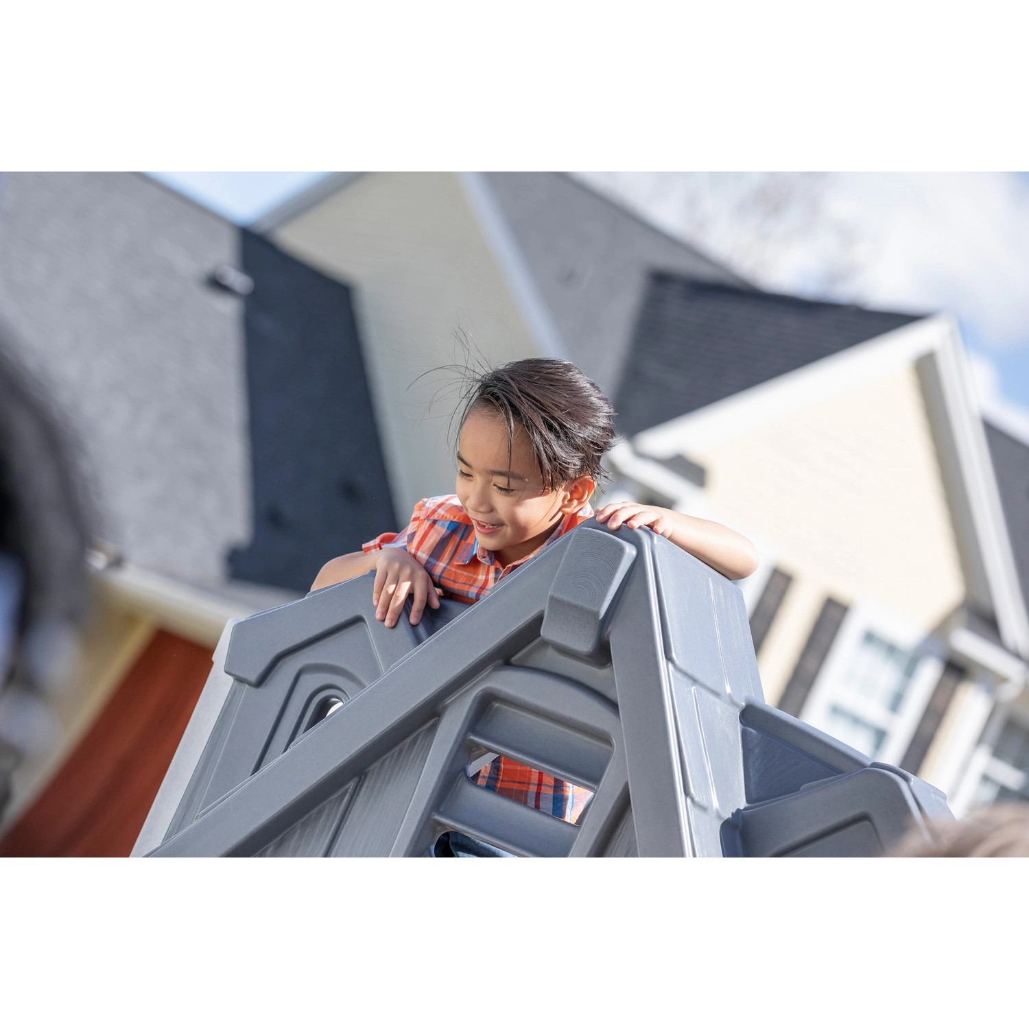 Kind auf dem Step2 Spielhaus Adventures mit Rutsche im Garten.