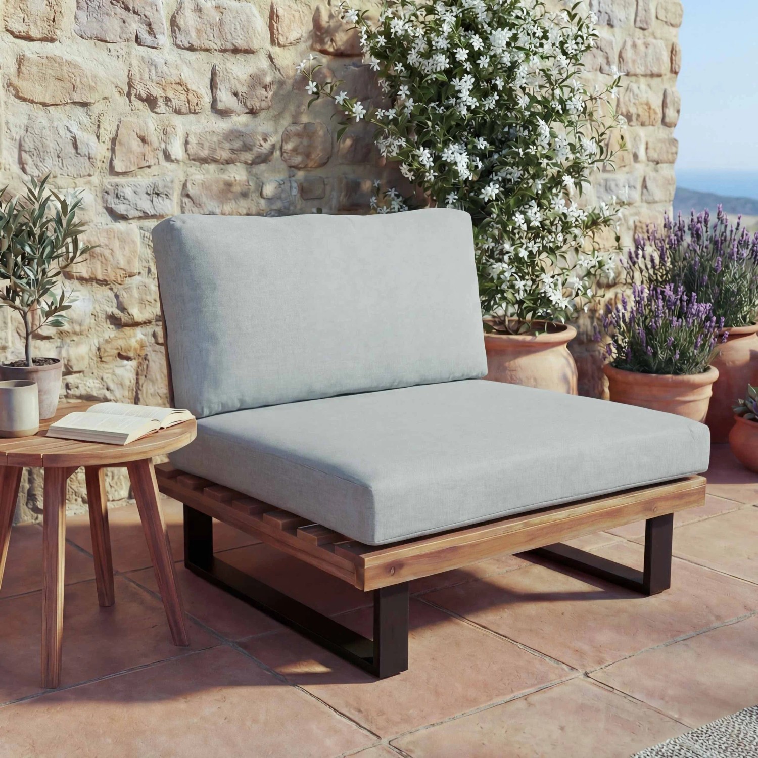 MCW Lounge-Sessel H54 aus hellbraunem Akazienholz mit hellgrauen Polstern auf einer sonnigen Terrasse.