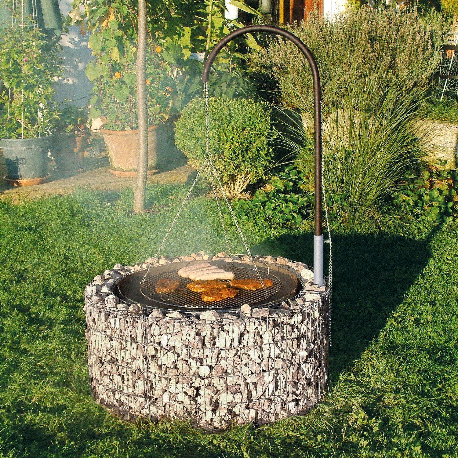 Bellissa Gabionen Grill- und Feuerstelle mit Grillrost und schwenkbarem Grillarm im Garten.