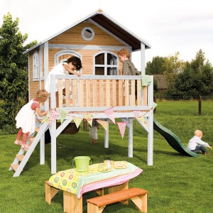 Axi Spielhaus Sophie mit Rutsche, braun/weiß, mit spielenden Kindern im Garten.