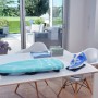 Leifheit AirBoard Compact Tischbügelbrett mit blauem Bezug und Bügeleisen auf einem Tisch.