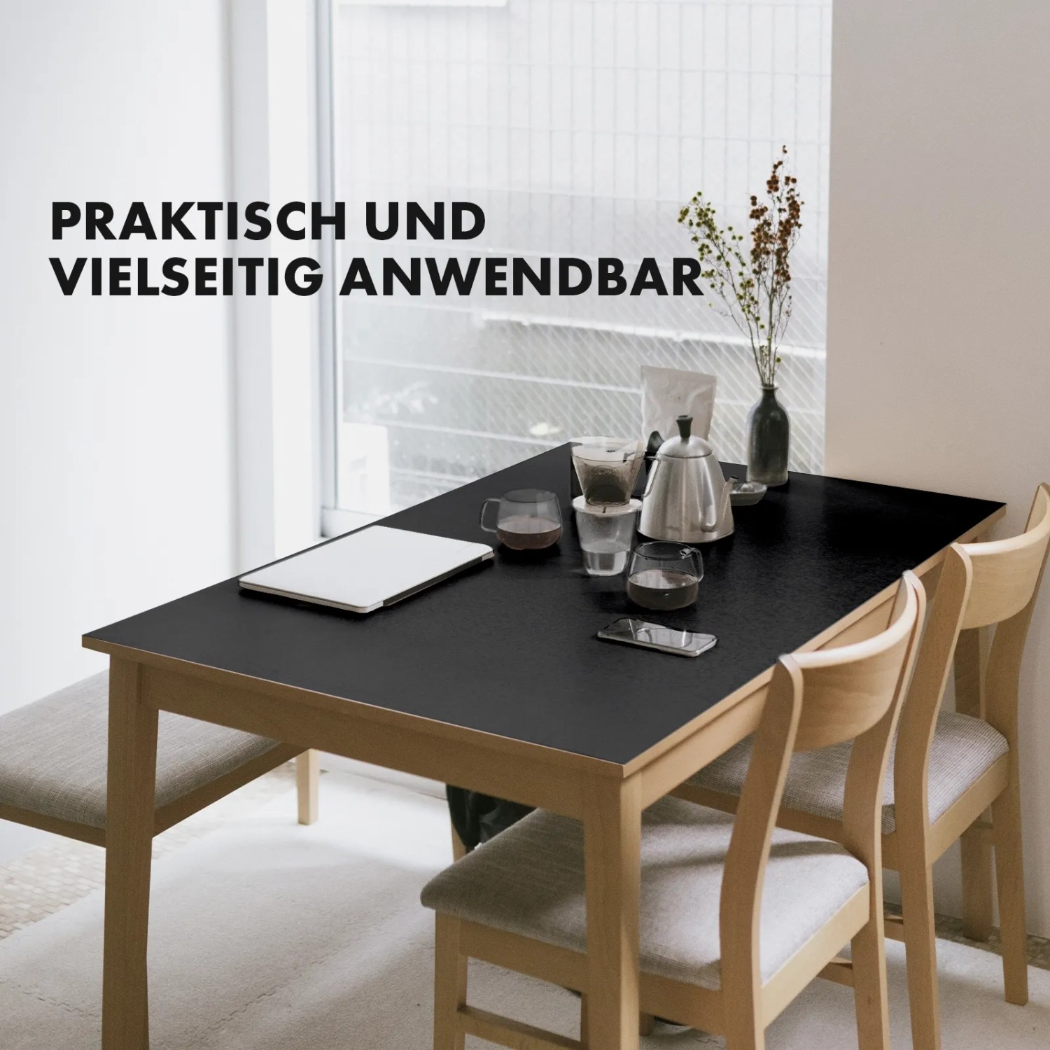 Schwarze KARAT Tischfolie Empire auf Esstisch mit Geschirr und Laptop.