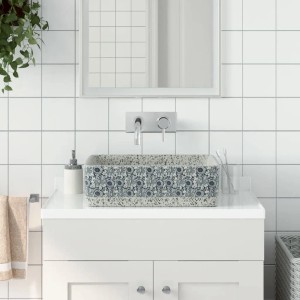 Rechteckiges Aufsatzwaschbecken in Grau-Blau mit floralem Muster auf einem weißen Waschtisch.