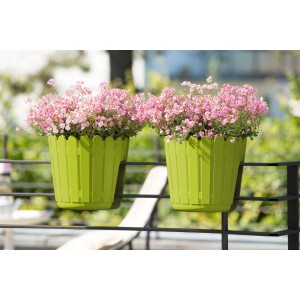 Zwei grüne Poétic Landhaus Geländertöpfe mit rosa Blumen am Balkongeländer.