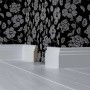 Weiße Sockelleiste White&Black Stil (70x18x2500mm) vor floral gemusterter Wand auf hellem Holzboden.