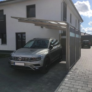 Ximax Einzelcarport Linea-110 in Edelstahl-Look Aluminium mit transparentem Dach schützt silbernes SUV vor modernem Haus.