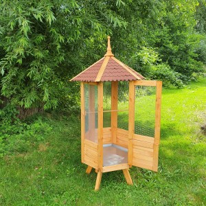 Sechseckige Promadino Vogelvoliere aus Holz mit Bitumendach und offener Tür im Garten.