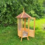 Sechseckige Promadino Vogelvoliere aus Holz mit Bitumendach und offener Tür im Garten.