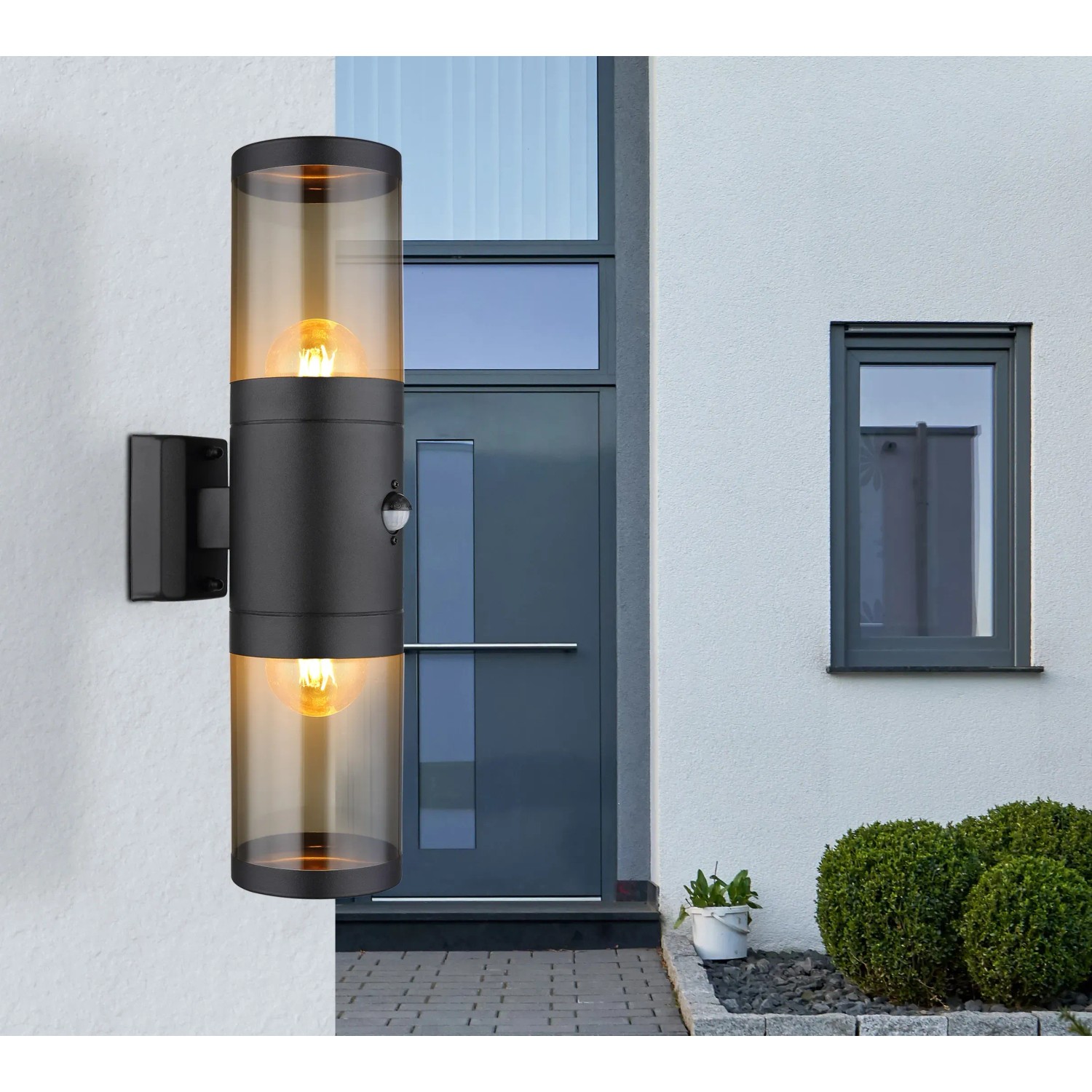 Moderne, schwarze Globo Außenleuchte mit zwei Lampen und Bewegungssensor an einer weißen Hauswand.