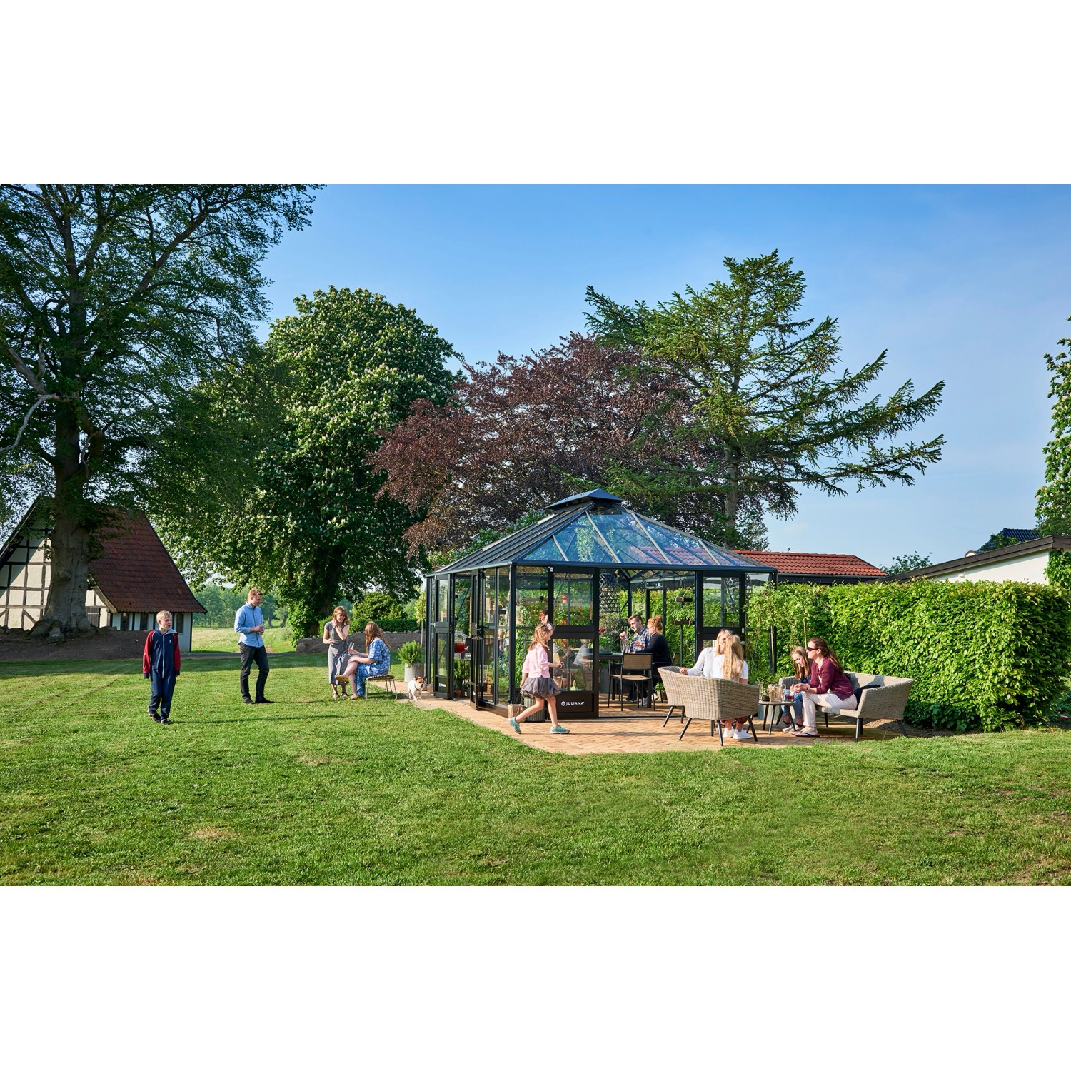 Juliana Gewächshaus Grand Oase 18 in Anthrazit-Schwarz mit Personen im Garten.