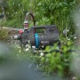 Gardena Akku-Gartenpumpe 3000 Silent 18V im Garten, umgeben von Pflanzen.