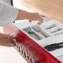 Weißer ausziehbarer Besteckkasten aus Kunststoff in roter Schublade. Hände sortieren Besteck für mehr Ordnung.