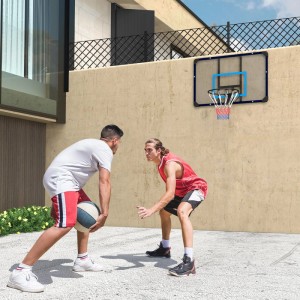 Zwei Männer spielen Basketball mit einem wandmontierten SPORTNOW Basketballkorb mit transparenter Rückwand und blauem Rand im Garten.
