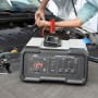 AEG Batterieladegerät CW10 vor einem Auto mit angeschlossenen Batterieklemmen.