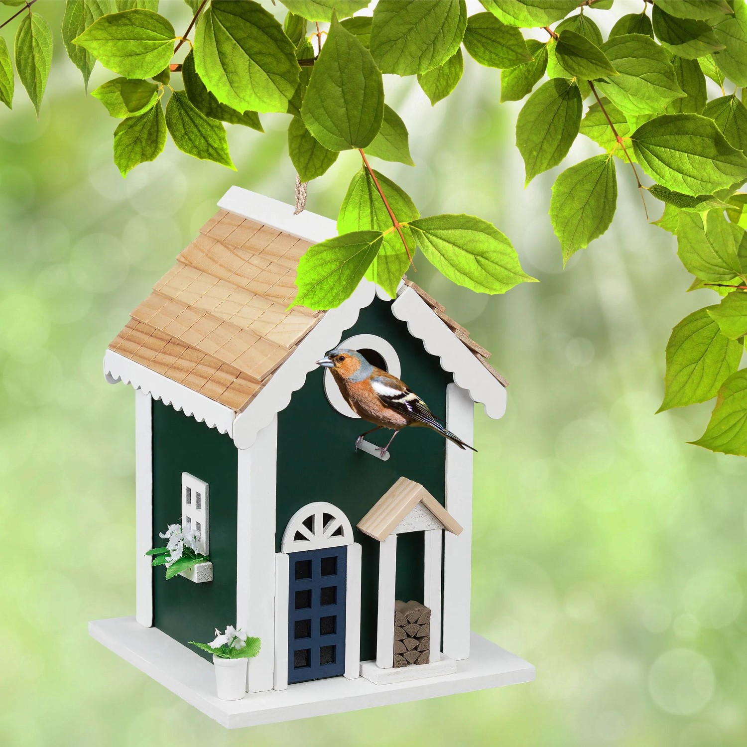 Grünes Vogelhaus im Landhausstil aus Holz, mit weißem Dach und einem Vogel am Flugloch. Ideal als Nistkasten für Wildvögel.