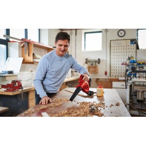 Mann benutzt Einhell Akku-Bläser TE-CB 18/180 Li-Solo zum Säubern einer Werkbank von Holzspänen.