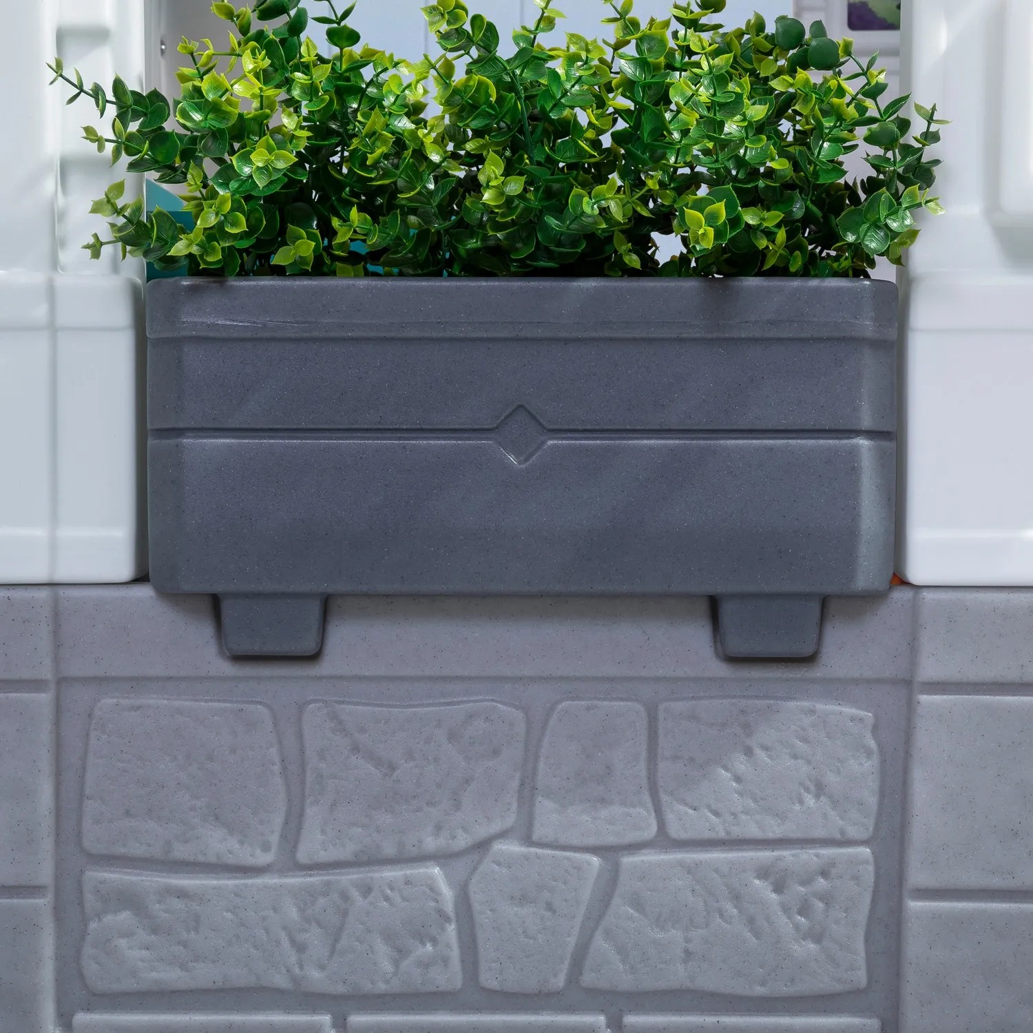 Detailansicht: Step2 Spielhaus Neat & Tidy Cottage mit grauem Blumenkasten und grünen Pflanzen.