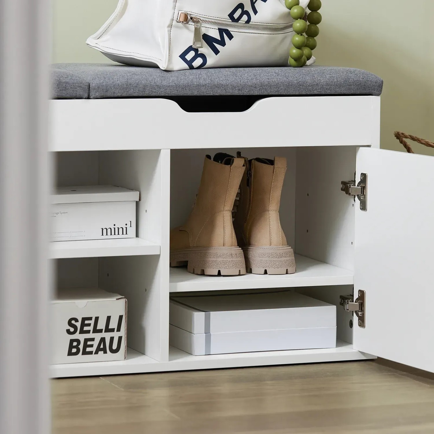 Weiße Schuhbank mit grauem Sitzkissen und Stauraum für Schuhe und Accessoires.