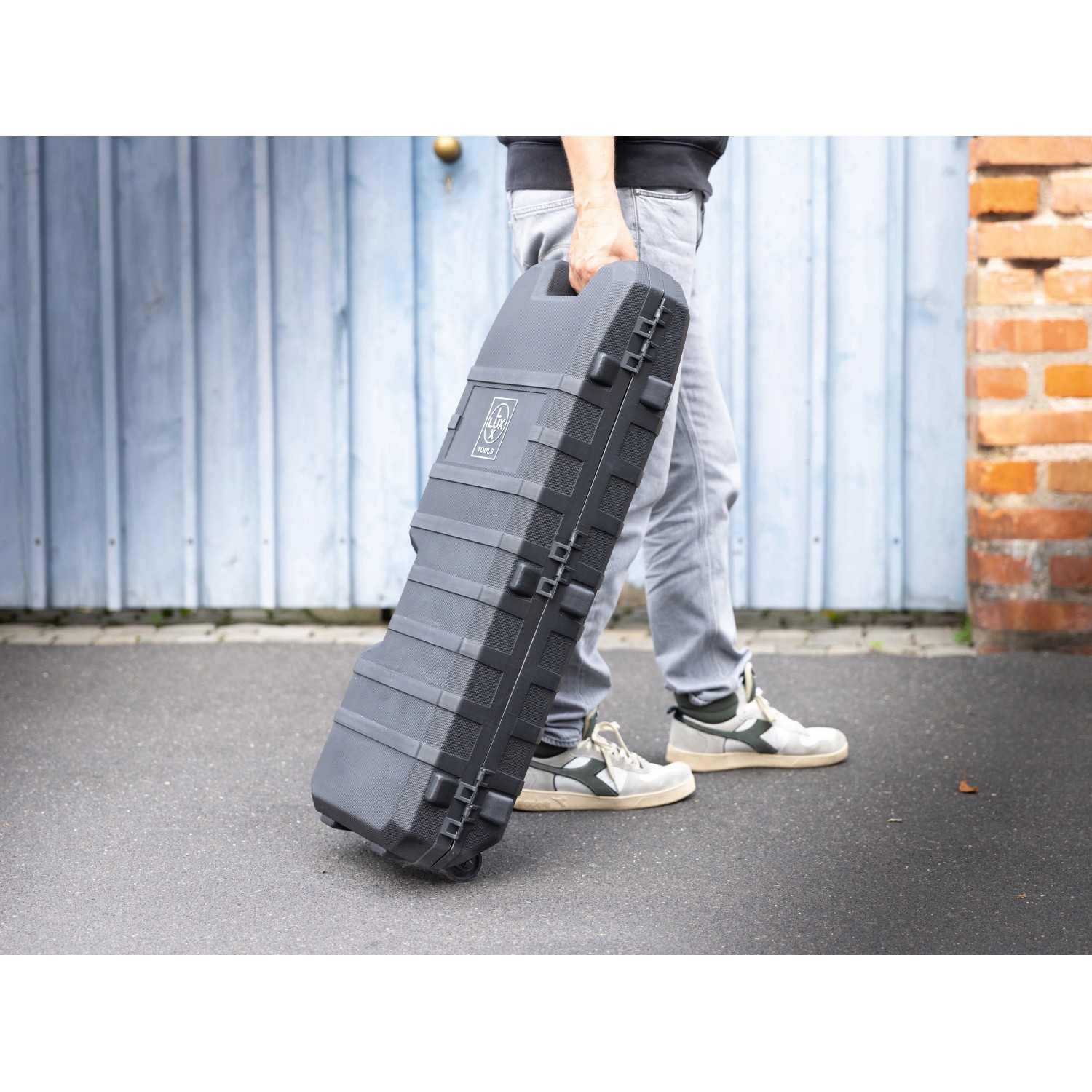 Mann trägt LUX Abbruchhammer E-AHM-1700 im Koffer. Baumaschine für Abbrucharbeiten.