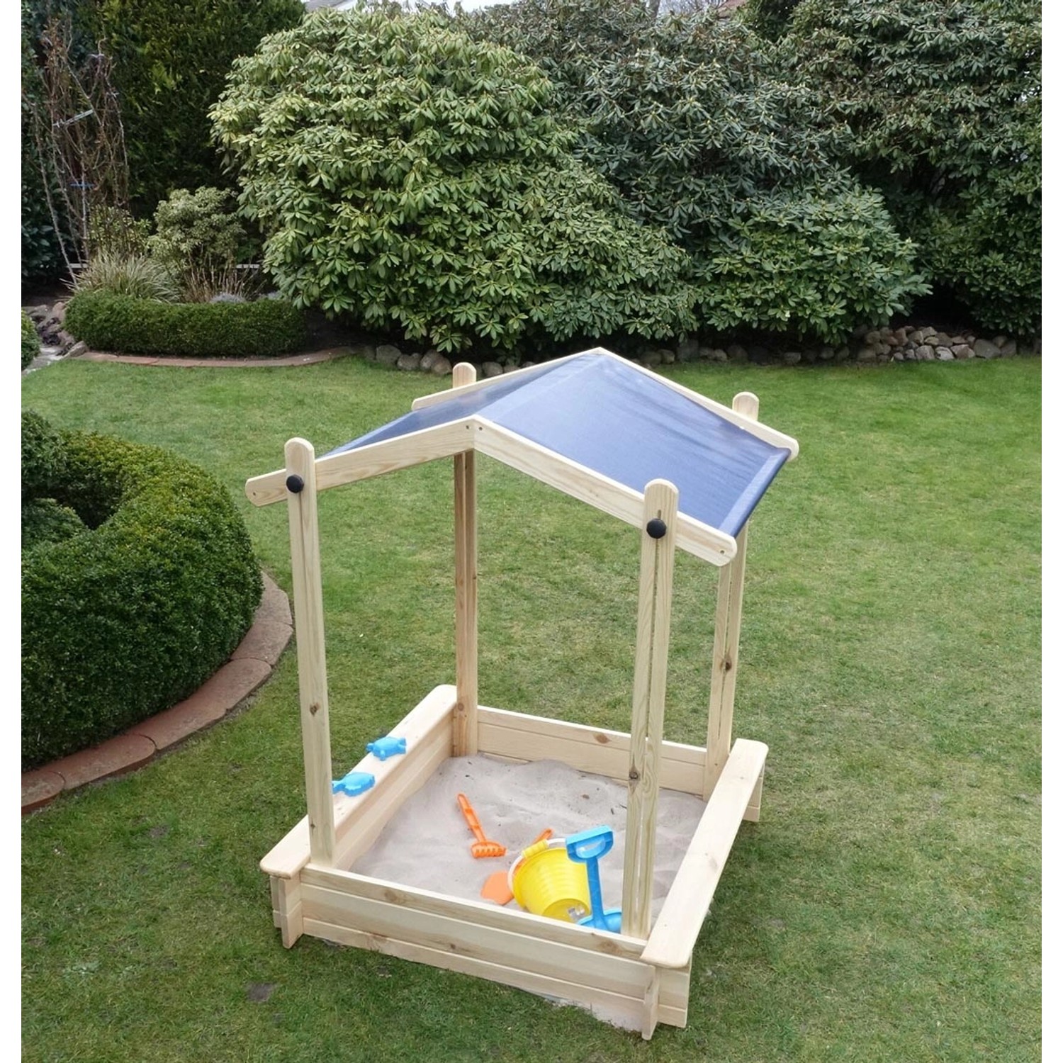 Promadino Sandkasten Peter mit absenkbarem Dach und Spielzeug im Garten.