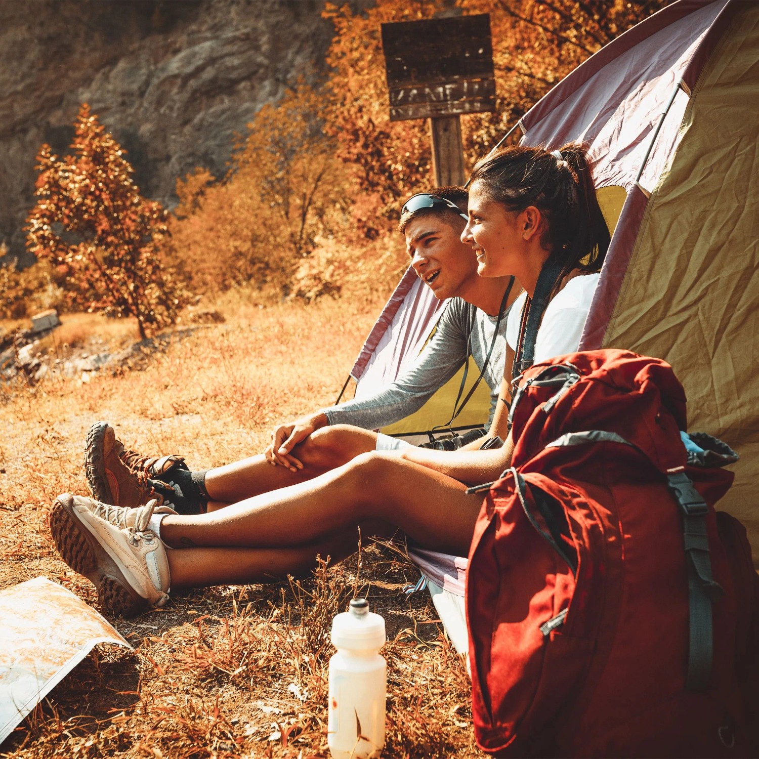 Zwei Personen beim Camping vor einem Zelt. Ideal für Outdoor-Abenteuer mit einem Edelstahl Flachmann.